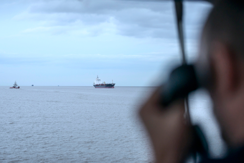 Ein Kapitän schaut durch das Fenster auf die See und andere Schiffe.